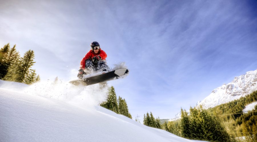 Mann springt mit einem Snowboard über Schnee